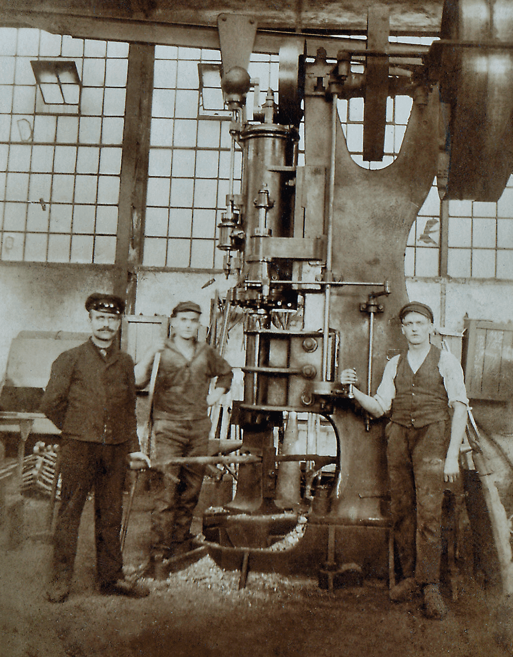 Vanha kuva, jossa näkyy kolme työntekijää AERZEN-aggregaatin edessä