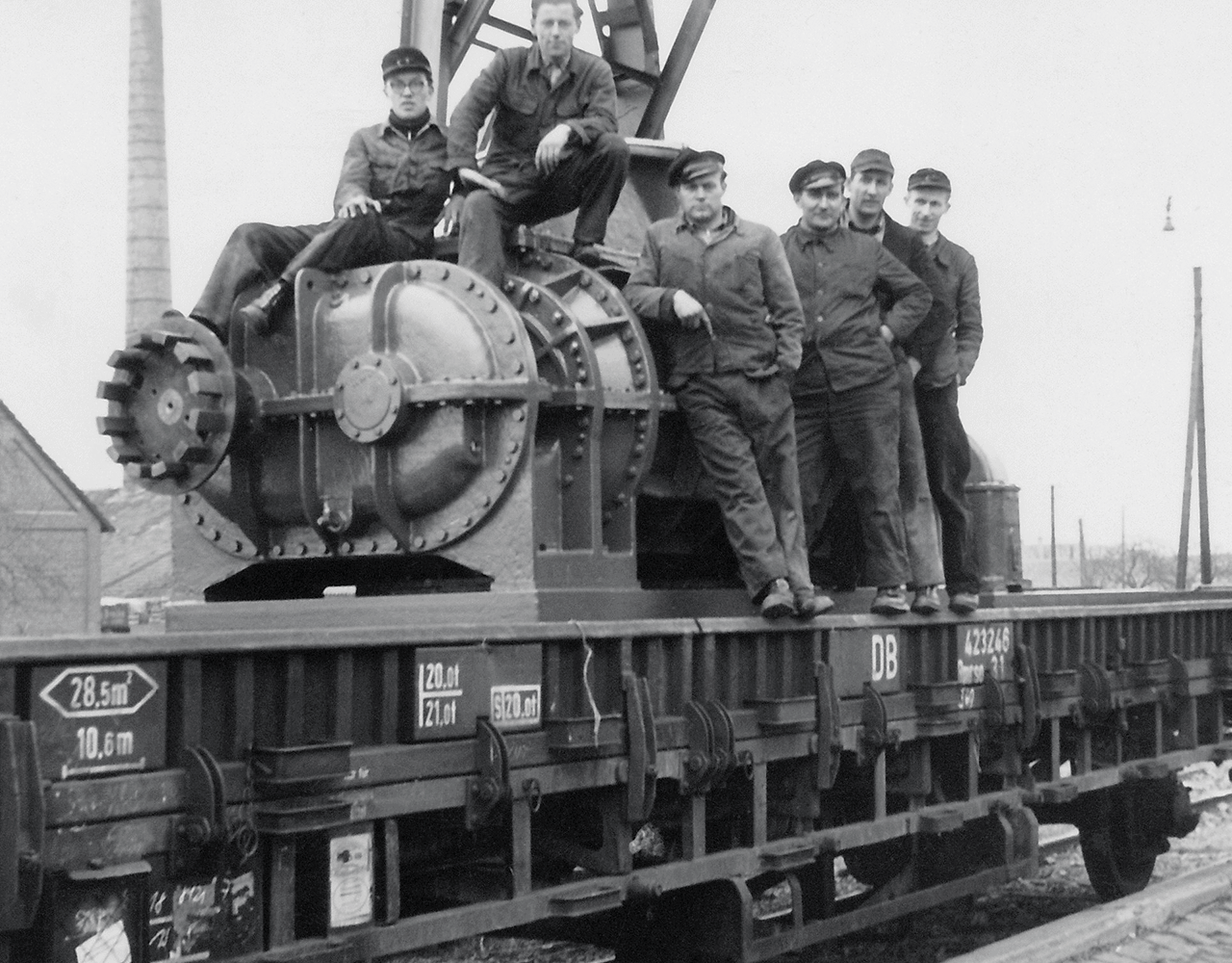 Obrázek zaměstnanců sedících na objemovém dmychadle, které se odesílalo do Berlína po železniční trati